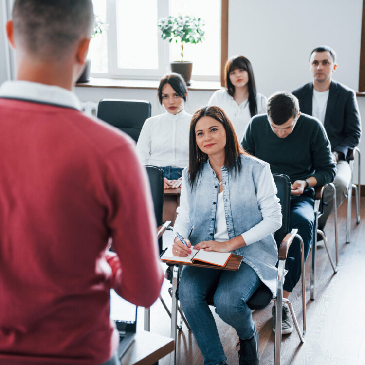 In red shirt. Group of people at business conference in modern classroom at daytime